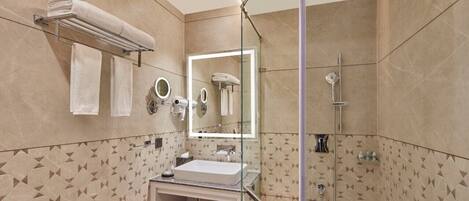 A modern bathroom with a glass-enclosed shower, a vanity with a sink, and a large mirror.