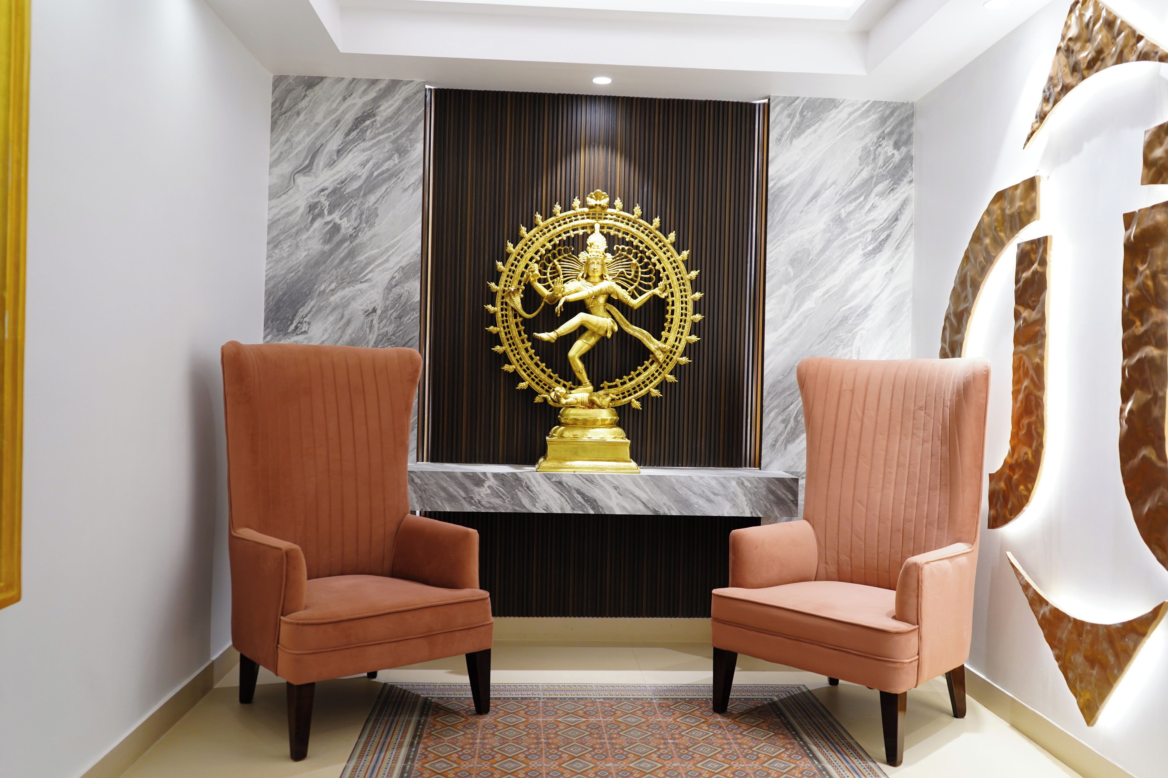 Una zona de recepción con dos sillones cómodos, una pared de mármol y una estatua dorada.