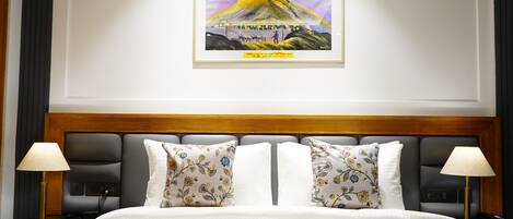 A hotel room with a large bed, two nightstands, a framed picture on the wall, and a wooden headboard.