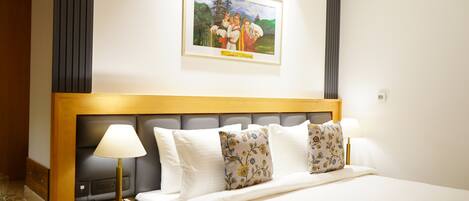 A hotel room with a bed, bedside lamps, a phone, and a framed picture on the wall.