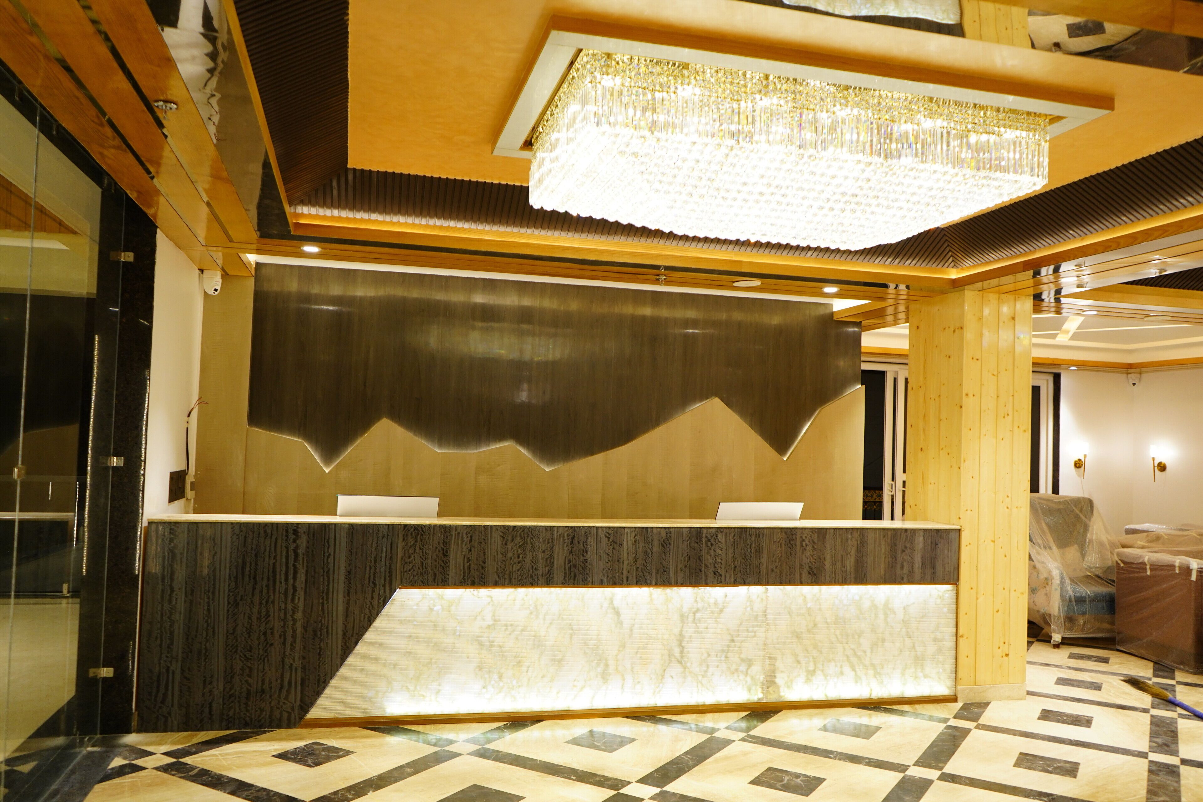 A reception area with a marble counter, a large chandelier, and a checkered floor.