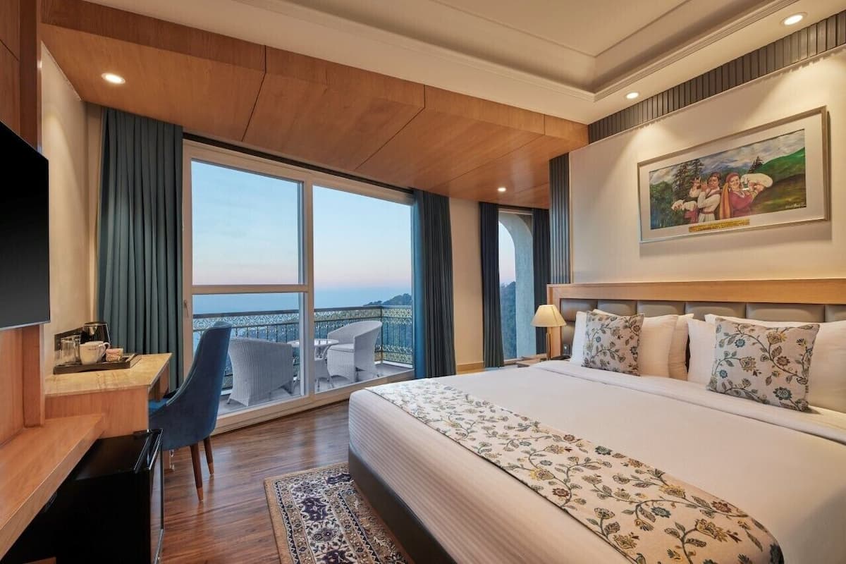 Een hotelkamer met een groot bed, een bureau met stoel, een televisie en een balkon met uitzicht.