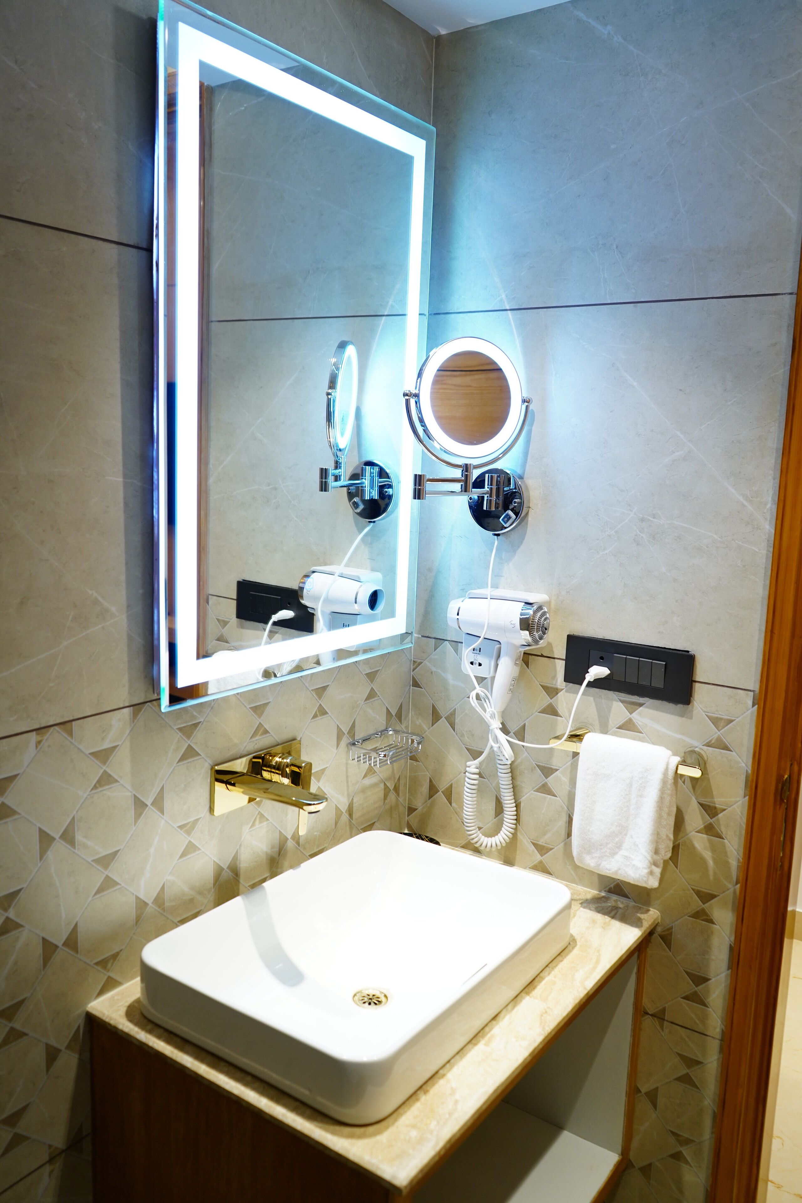 A bathroom with a large mirror, a hairdryer, a towel rack, and a sink.