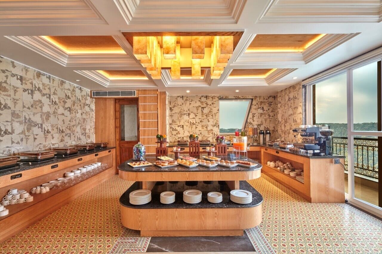 Ein reichhaltiges Frühstücksbuffet mit verschiedenen Speisen, einer Kaffeestation und Blick ins Freie.