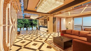 Een hotel lobby met een receptiebalie, een zitgedeelte met banken en een vloer met patroon.