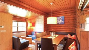 L’intérieur d’un chalet en bois comprend une table à manger, des chaises, un canapé et un banc.