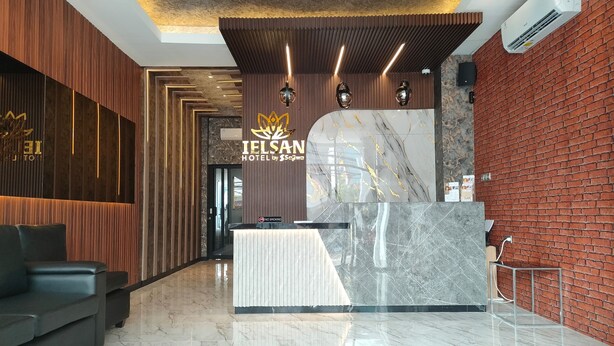 Zona de recepción de un hotel con un mostrador de mármol, un cartel de 'No Fumar' y un letrero de 'Telsan Hotel by Ssaya'.