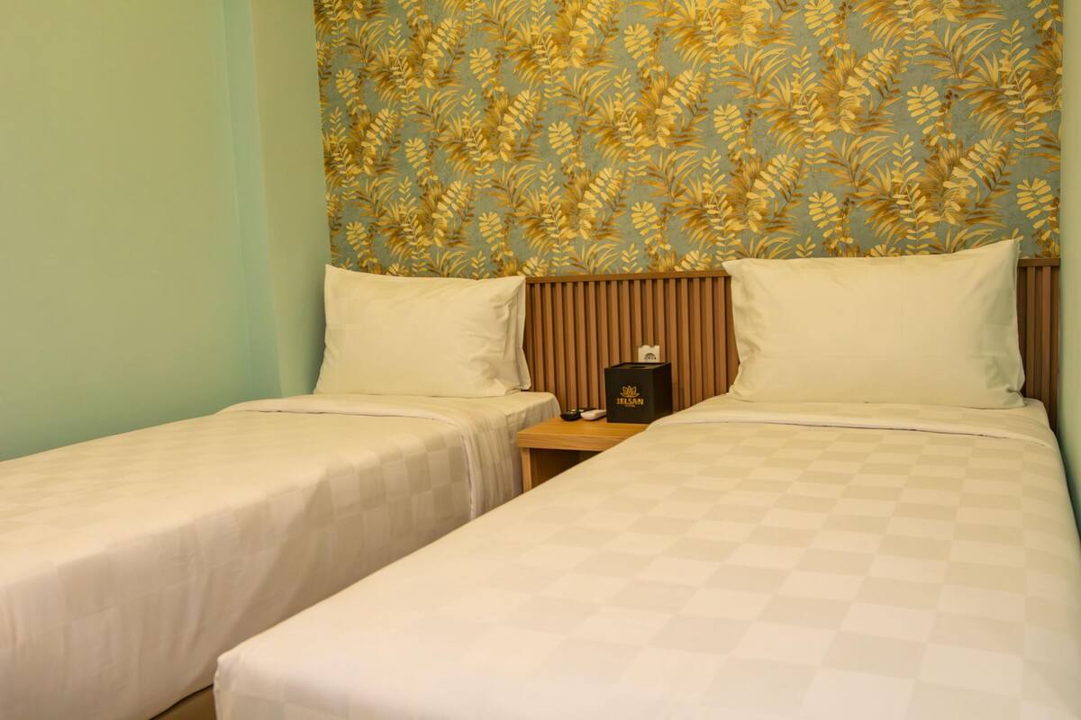 Una habitación de hotel con dos camas individuales, cabecera de madera y diseño de papel tapiz floral.