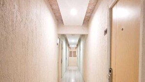 Un pasillo largo y estrecho con piso de baldosas y paredes lisas, que conduce a una puerta al final.
