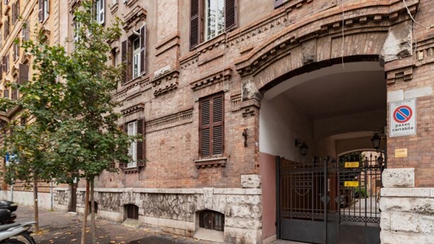 Ein historisches Gebäude mit einem verschlossenen Eingang, einem Baum und einem abgestellten Motorrad.