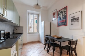 A kitchen with a sink, stove, and cabinets, a dining table with chairs, and a window.