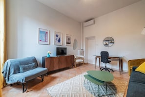 A living room with a sofa, a small table, a TV, and a chair.