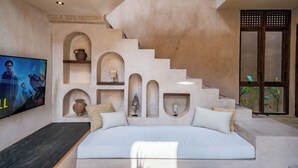 Une chambre avec un grand lit, une télévision et un escalier doté d’étagères intégrées.