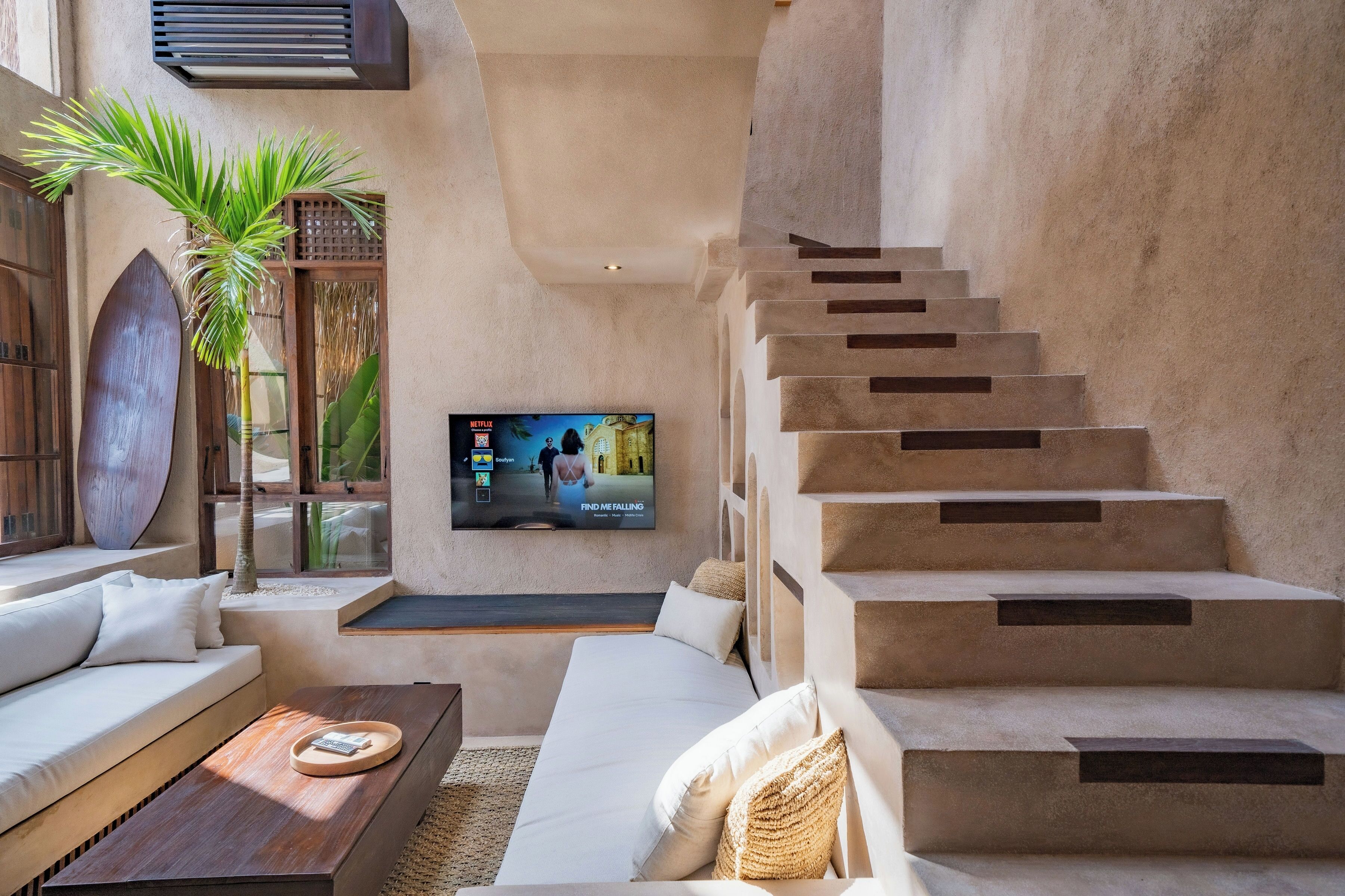 A modern interior with a staircase, a flat-screen TV, a sofa, and a coffee table.