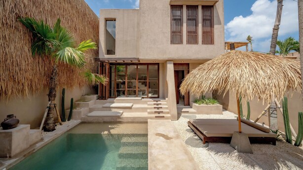 Une maison moderne dotée d’une piscine, d’un toit de chaume et d’un design minimaliste.