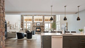 A spacious kitchen with a large island, dark cabinets, and pendant lighting. - Breathtaking Mountain Manor, Huge Deck w/ Hot Tub, Everything High End and New, 1 Mile to Ski Slopes (Granby)