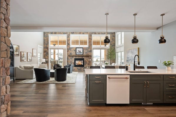 A spacious kitchen with a large island, dark cabinets, and pendant lighting.