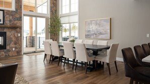 A dining area with a stone wall, large windows, and a modern table and chairs. - Breathtaking Mountain Manor, Huge Deck w/ Hot Tub, Everything High End and New, 1 Mile to Ski Slopes (Granby)