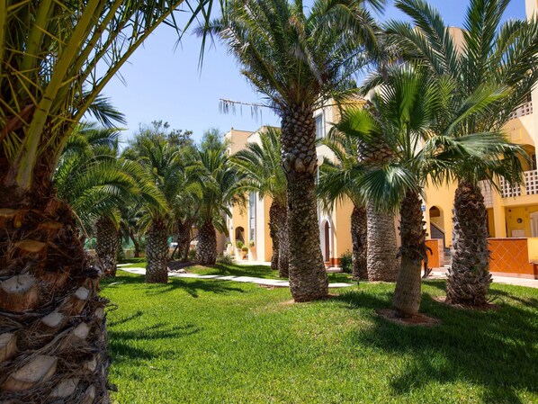 A courtyard with palm trees and a building with a yellow facade. - Lively Apartment With Large Pool (Roquetas de Mar)