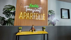 Seinä, jossa on neonvalomainos, jossa lukee ”freddo Transient APARTELLE”, ja puupaneelista tehty koristelu.