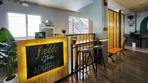 Moderni sisustus, jossa on vastaanottotiski, jossa lukee »fredo Studio APARTELLE», puuelementtejä ja suuri ikkuna, jossa on sälekaihtimet.