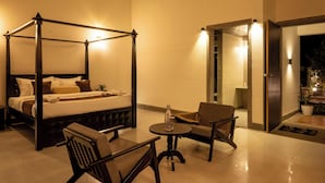 A four-poster bed with a bedside table and two chairs in a well-lit room with a view of the outside. - Amora A Boutique Resort (Paud)