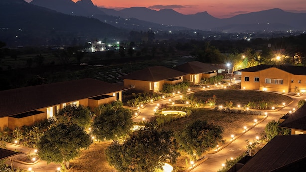 A residential area with houses, a well-lit driveway, and a mountainous backdrop. - Amora A Boutique Resort (Paud)