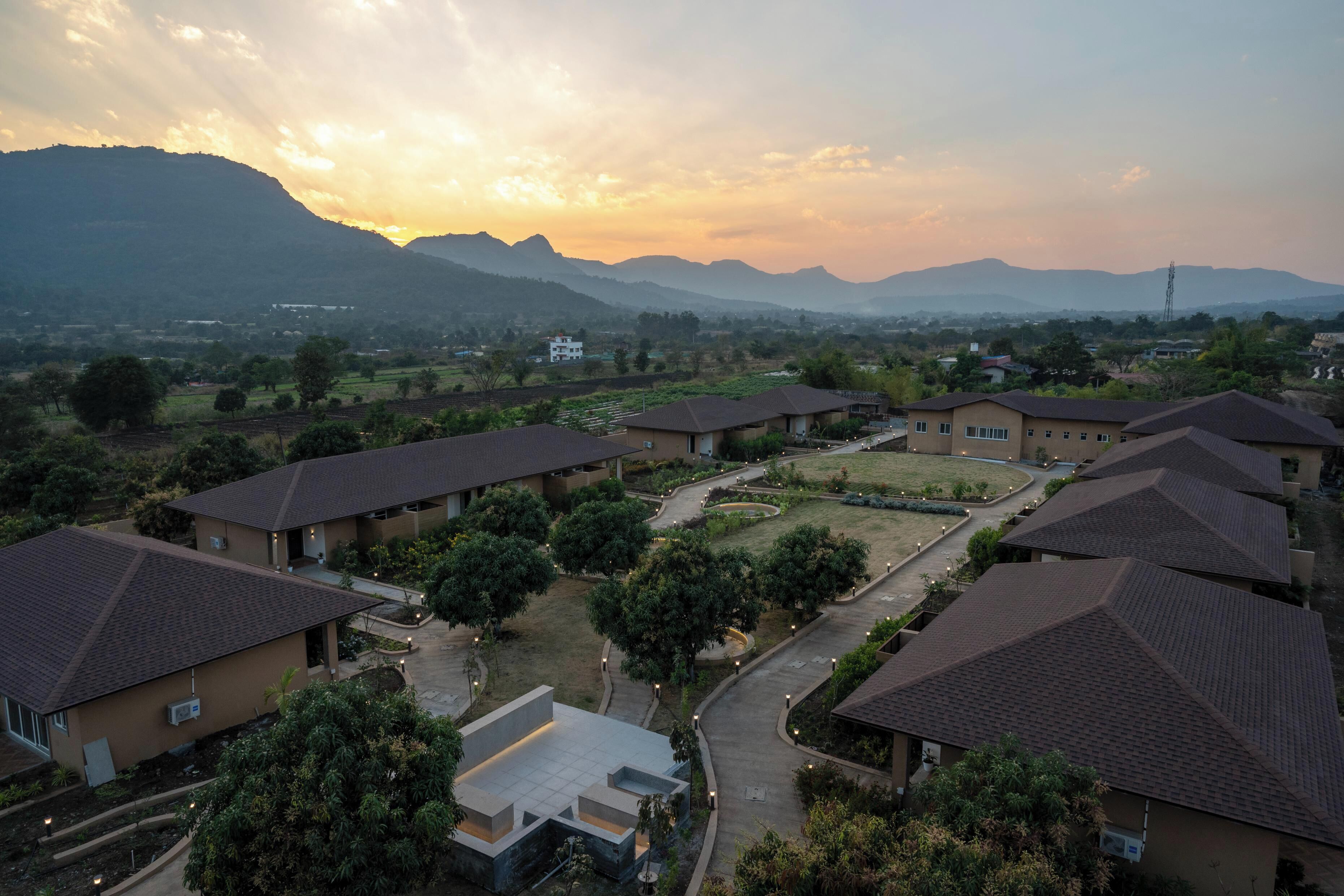 A residential area with multiple houses, a central paved area, and distant mountains.
