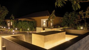A nighttime view of a modern outdoor area with geometric planters and ambient lighting. - Amora A Boutique Resort (Paud)