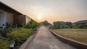 A pathway leading to a building with a modern design, surrounded by greenery and a clear sky. - Amora A Boutique Resort (Paud)