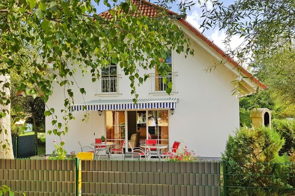 A two-story house with a balcony, a fenced garden, and a red-tiled roof. - Cottages at the Kummerower See in Verchen (Verchen)