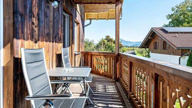 A wooden deck with a table and chairs, a pergola, and a view of a mountain and a house. - Apartment 'Untersbergblick' with Mountain View, Balcony and Wi-Fi (Freilassing)