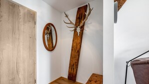 A hallway with a wooden door, a mirror, a wooden wall decoration, and a small table. - Apartment 'Untersbergblick' with Mountain View, Balcony and Wi-Fi (Freilassing)