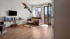 A modern living room with a sofa, coffee table, and bookshelves. - Apartment 'Untersbergblick' with Mountain View, Balcony and Wi-Fi (Freilassing)