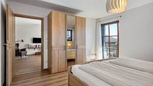 A bedroom with a bed, wooden wardrobe, a mirror, a window, and a lamp. - Apartment 'Untersbergblick' with Mountain View, Balcony and Wi-Fi (Freilassing)