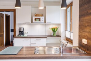 Une cuisine moderne avec des armoires blanches, un évier en acier inoxydable, un four à micro-ondes et une machine à café.