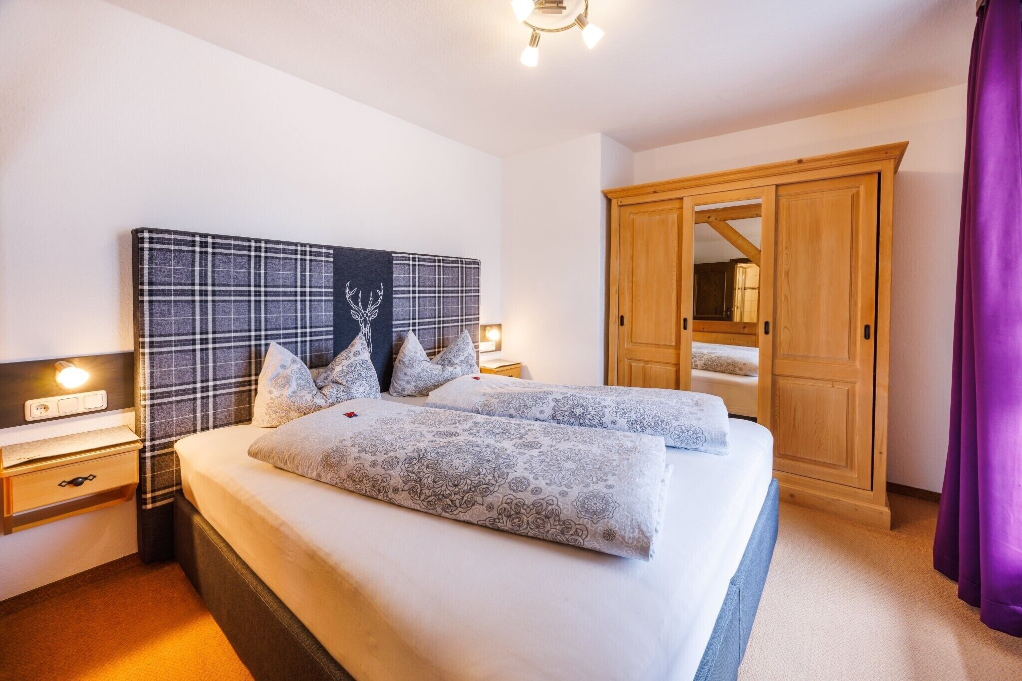 Ein Schlafzimmer mit Bett, Nachttischen, einem Kleiderschrank und einem Spiegel.
