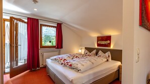 Ein Schlafzimmer mit einem Bett, einem Fenster mit Vorhängen, einem Heizkörper und einem Bild an der Wand.
