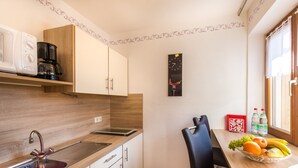 A modern kitchen with a microwave, coffee maker, and a fruit bowl on the counter.