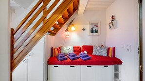 A bedroom with a built-in bed, a wooden staircase, a wall-mounted shelf, and a single light fixture. - Holiday Apartment 'Lila' with Shared Garden and Private Beach Chair (Nordstrand)