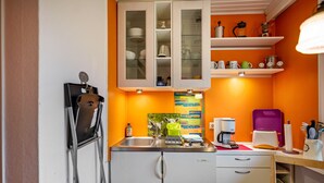 A compact kitchen with a refrigerator, a sink, a toaster, and a coffee maker. - Holiday Apartment 'Lila' with Shared Garden and Private Beach Chair (Nordstrand)