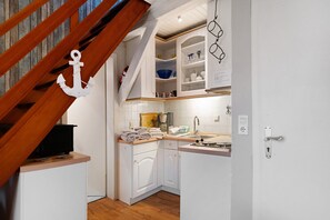 Une cuisine avec des meubles blancs, un escalier en bois et un porte-serviettes suspendu.