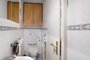 Une salle de bain équipée de toilettes, d’un porte-serviettes, d’un meuble en bois et d’un radiateur.