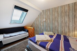 Une chambre à coucher comprenant un lit, un banc, une fenêtre et un mur recouvert de panneaux de bois verticaux.