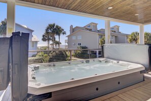 Ein Whirlpool auf einer Holzterrasse mit Blick auf eine Wohngegend und Palmen.