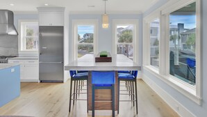 Una cocina moderna con una isla grande, electrodomésticos de acero inoxidable y taburetes de bar azules.