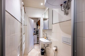 A narrow bathroom with a white sink, a mirror, and a towel rack.