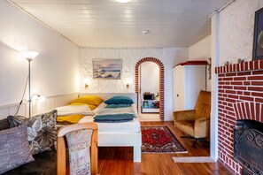 A cozy room with a bed, a chair, a fireplace, and a painting on the wall.