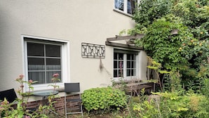 Een tuin met een tafel en stoelen, een houten bank en verschillende planten en bloemen.
