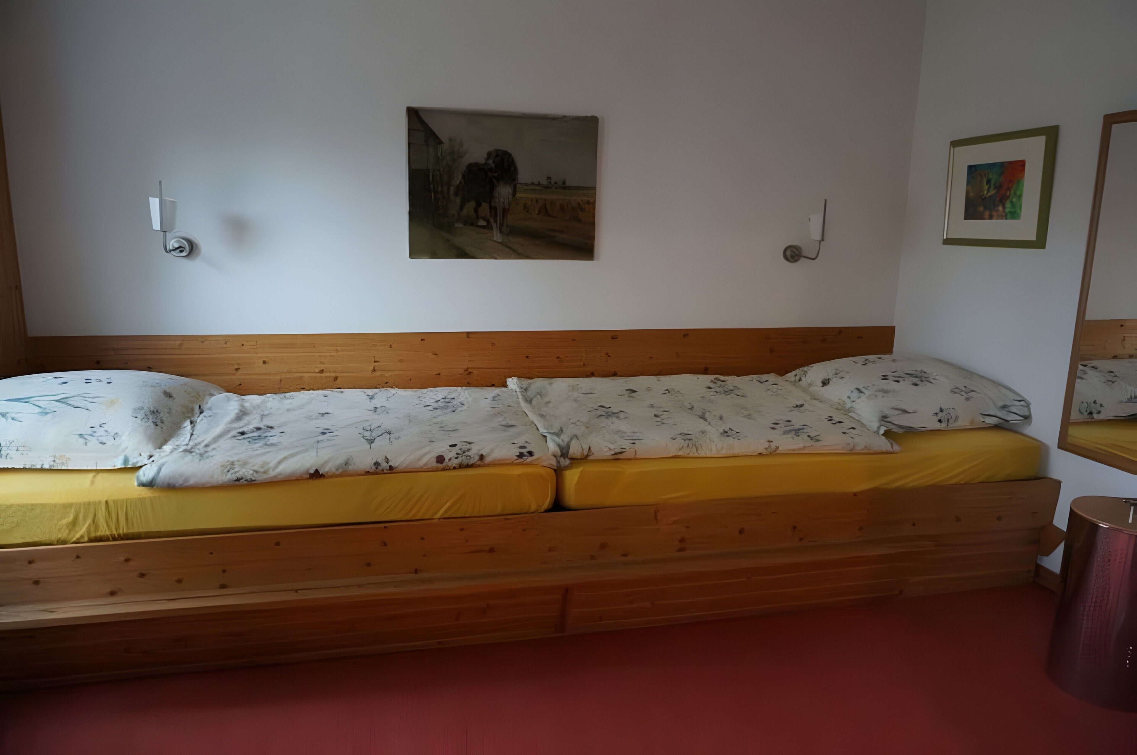 Un letto singolo con una testiera in legno, un materasso giallo e cuscini a motivi floreali.